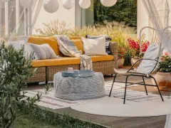 Relaks na tarasie w stylu boho: żółta kanapa, pleciony fotel, dywany i lampiony tworzą przytulną atmosferę.